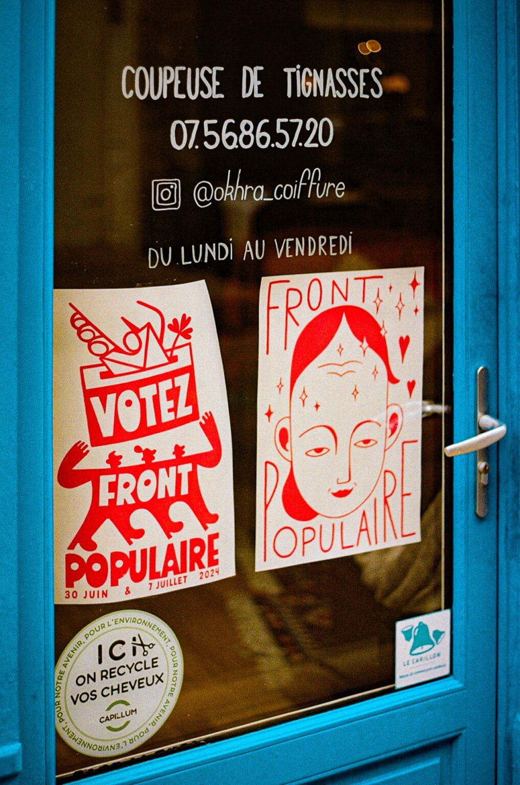 Devanture bleue du salon Õkhra Coiffure à Nantes avec affiches Front Populaire et autocollants.