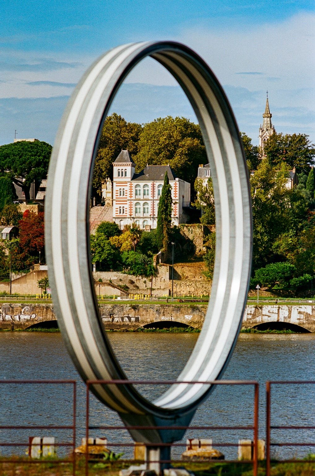 Anneau de Buren sur l’île de Nantes encadrant une maison bourgeoise sur la rive opposée de la Loire.