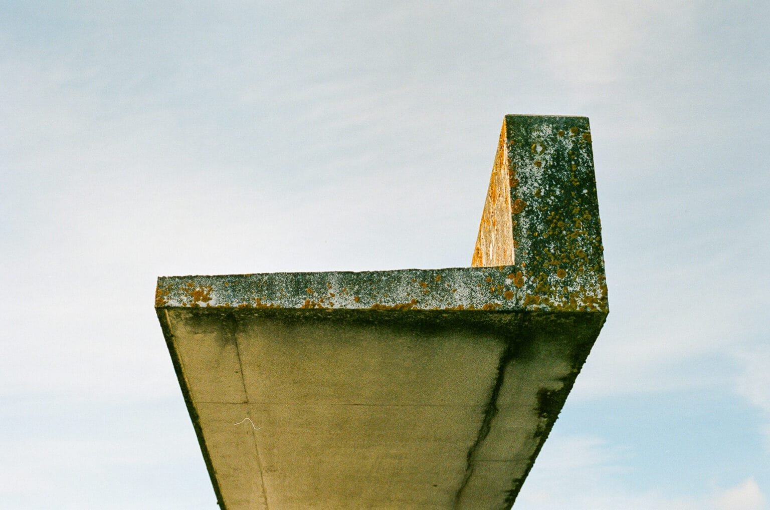 Mur en béton brut en surplomb à la base sous-marine de Saint-Nazaire, photographié en couleur sous un ciel clair.
