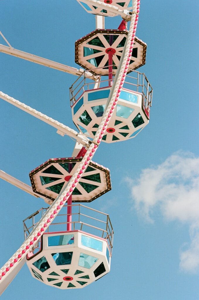 Cabines octogonales colorées d’une grande roue à la fête foraine de Nantes, sur fond de ciel bleu.