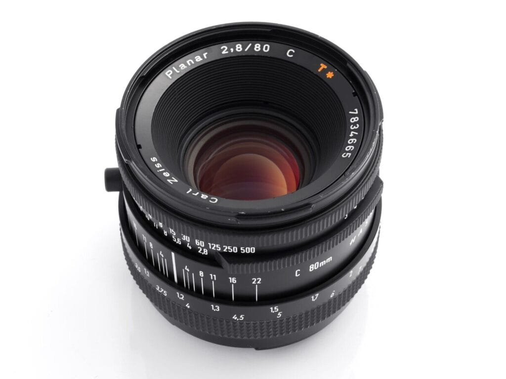 Objectif Carl Zeiss Planar 80mm f/2.8 T* vu de face, montrant l’optique et les inscriptions sur le pourtour.