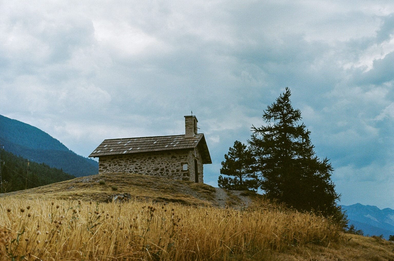Petite chapelle en pierre sur une colline, sous un ciel nuageux, près du lac de Siguret dans les Hautes-Alpes.