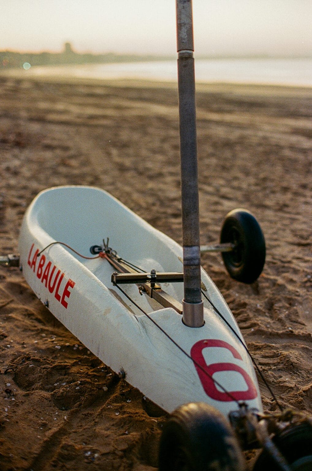 Char à voile blanc portant le numéro 6, posé sur le sable de la plage de La Baule au lever du soleil.