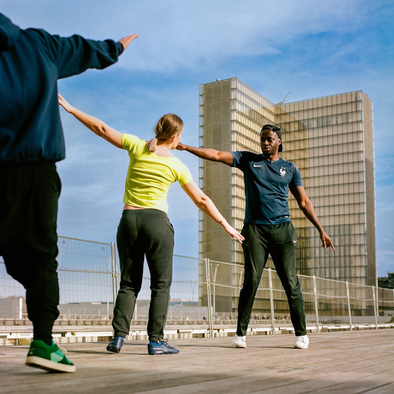 Groupe de danseurs en pleine répétition en extérieur, sur l’esplanade de la Bibliothèque François Mitterrand à Paris.