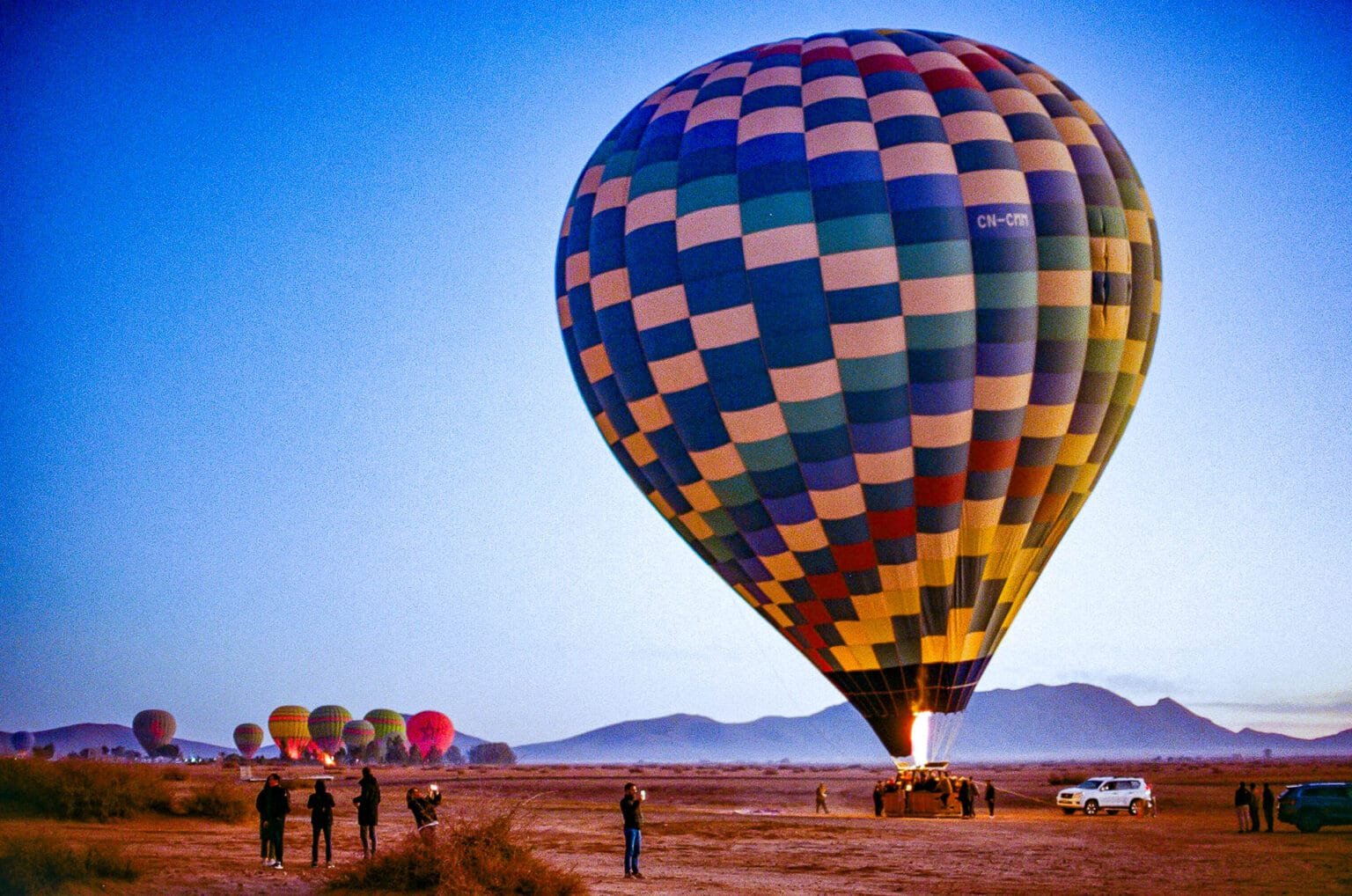 Montgolfière multicolore s’élevant dans le ciel du désert d’Agafay au lever du jour, au Maroc.