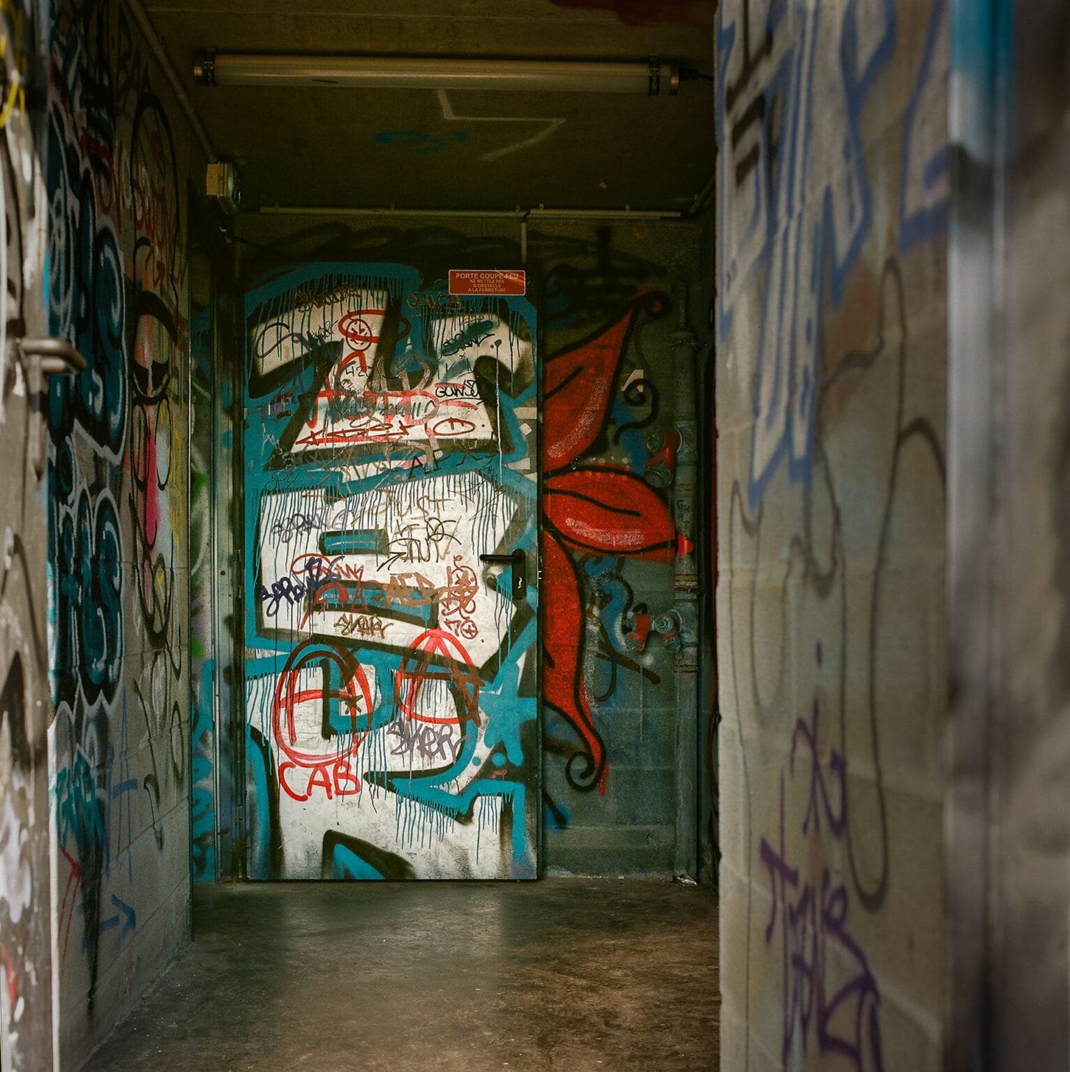 Entrée d’un parking à Nantes, recouverte de graffitis colorés sur les murs et la porte métallique.