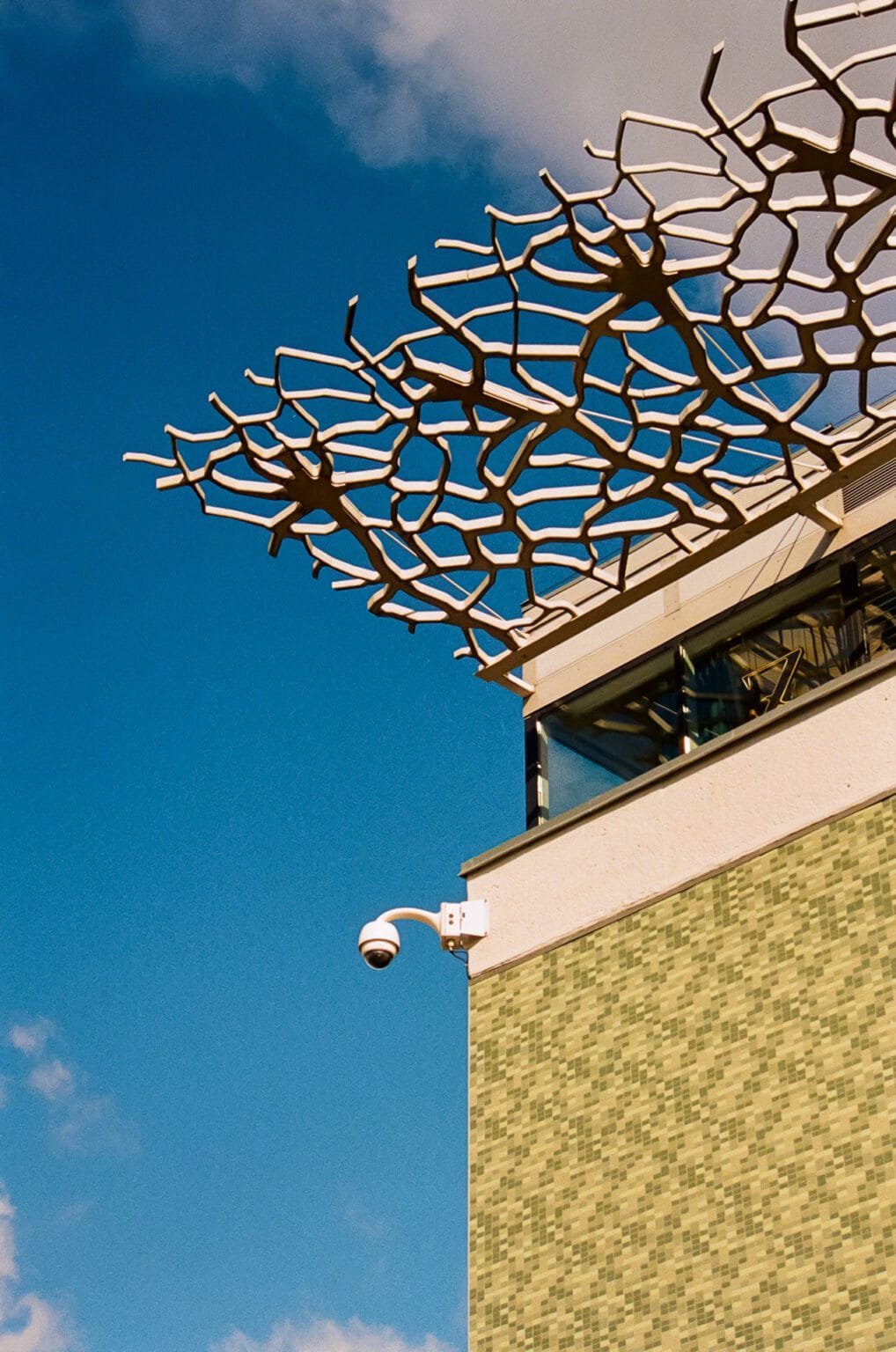 Façade du restaurant ZAW à la gare de Nantes, avec structure métallique ajourée et mur en carreaux verts, sous un ciel bleu.