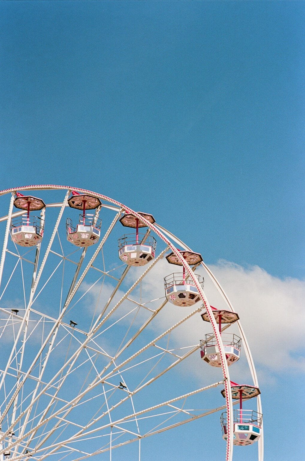 Grande roue blanche et rouge sur fond de ciel bleu, photographiée à la fête foraine de Nantes.