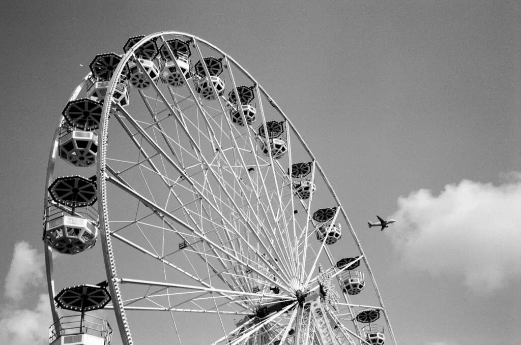 Grande roue de la fête foraine de Nantes en noir et blanc, avec un avion en arrière-plan dans le ciel.