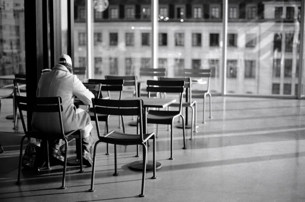Voyageur assis seul dans la salle d’attente de la gare de Nantes, photographié en noir et blanc.