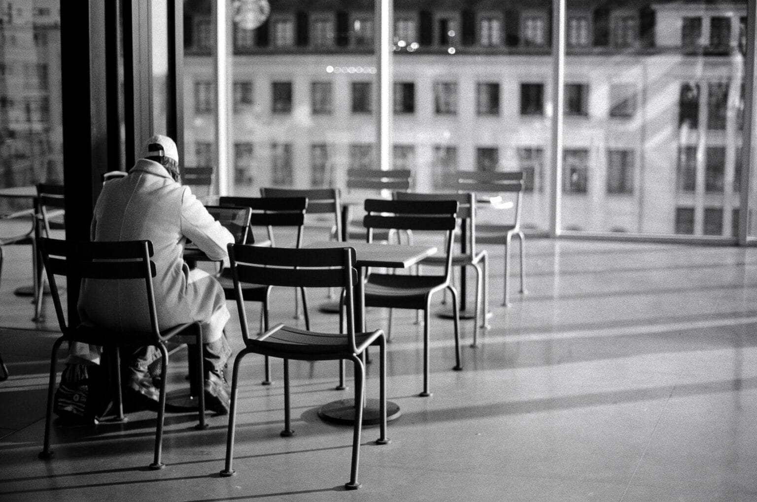 Voyageur assis seul dans la salle d’attente de la gare de Nantes, photographié en noir et blanc.