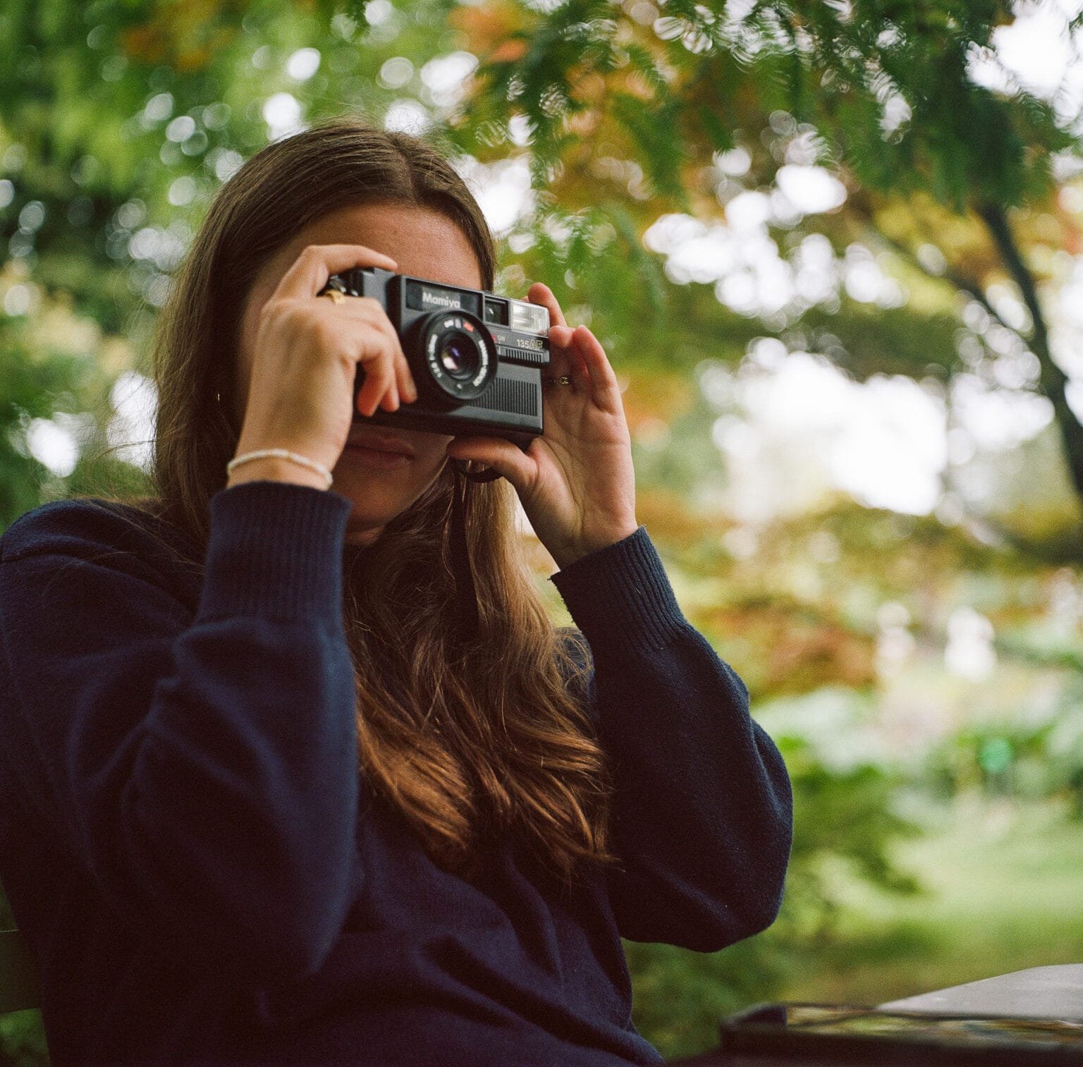 Jeanne en train d’essayer son appareil photo Mamiya 135, prise de vue en extérieur à Nantes en juillet 2024.