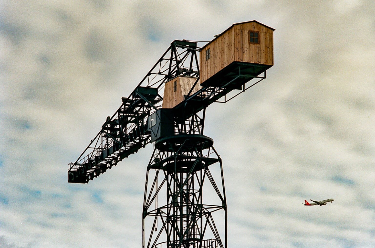 La grue noire de Nantes avec des cabanes en bois et un avion en arrière-plan.
