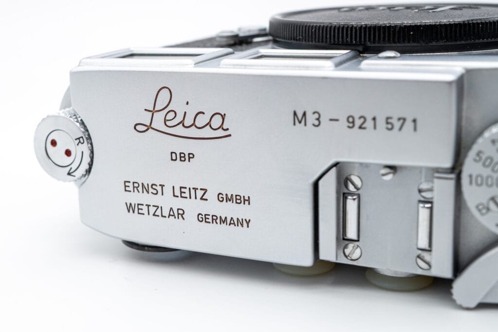 Gros plan sur le logo Leica, le numéro de série M3-921571 et les inscriptions “Ernst Leitz GmbH Wetzlar Germany” sur la plaque supérieure du Leica M3.