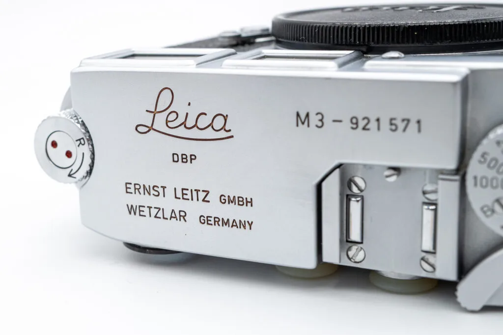 Gros plan sur le logo Leica, le numéro de série M3-921571 et les inscriptions “Ernst Leitz GmbH Wetzlar Germany” sur la plaque supérieure du Leica M3.