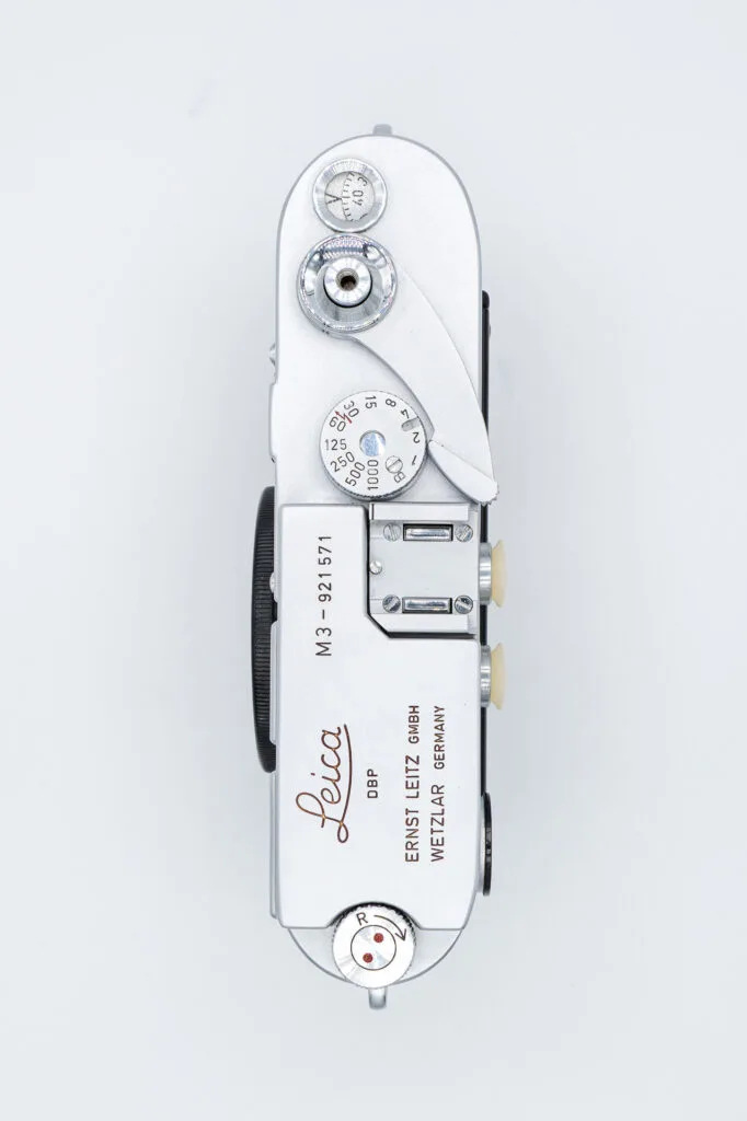 Vue de dessus du Leica M3, montrant la plaque supérieure avec la molette de sélection des vitesses, le levier d’armement et les gravures Leica.