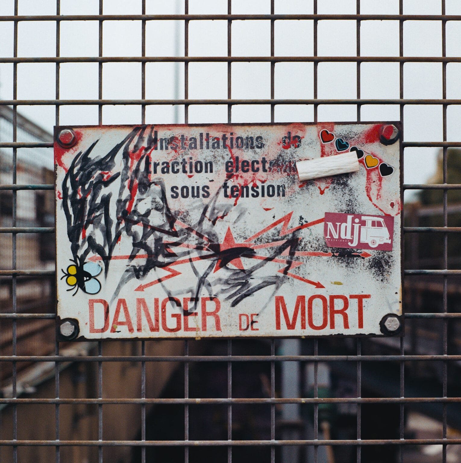Panneau “Danger de mort” tagué et recouvert d’autocollants sur un grillage à Nantes.