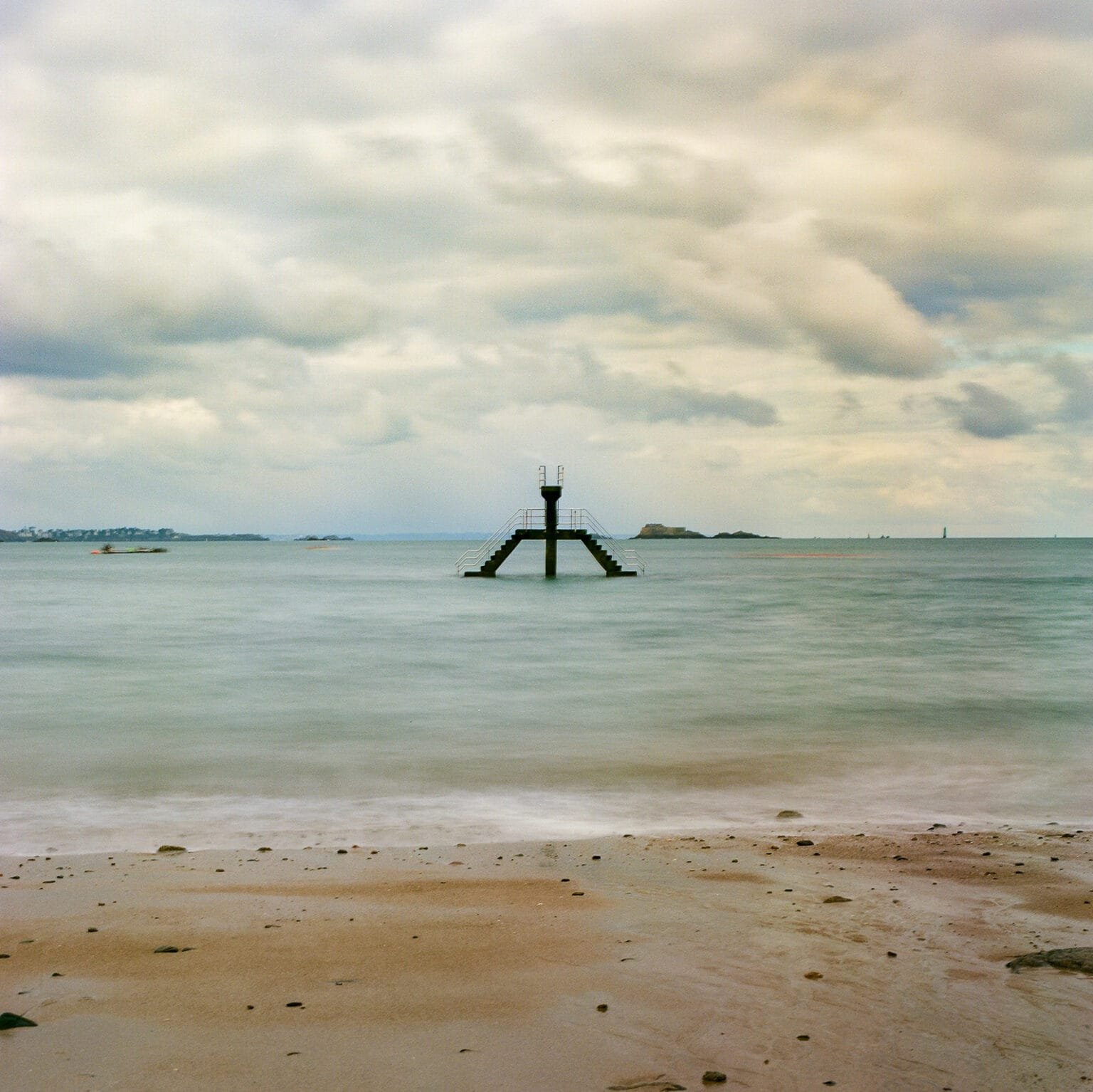 Vue de la piscine de Bon Secours à Saint-Malo à marée haute, sous un ciel nuageux.