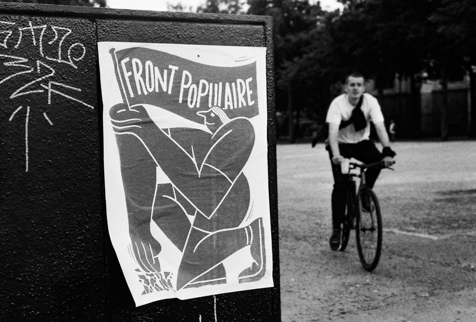 Affiche “Front Populaire” collée sur une borne noire, avec un cycliste en arrière-plan, place Saint-Pierre à Nantes.