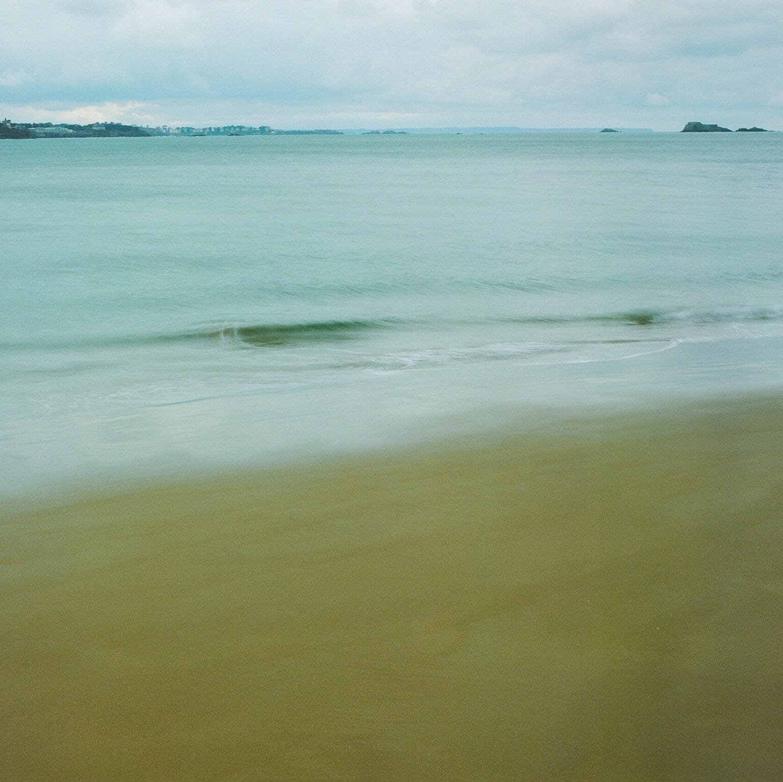 Vague douce sur le sable doré de la plage du Sillon à Saint-Malo, vue minimaliste.