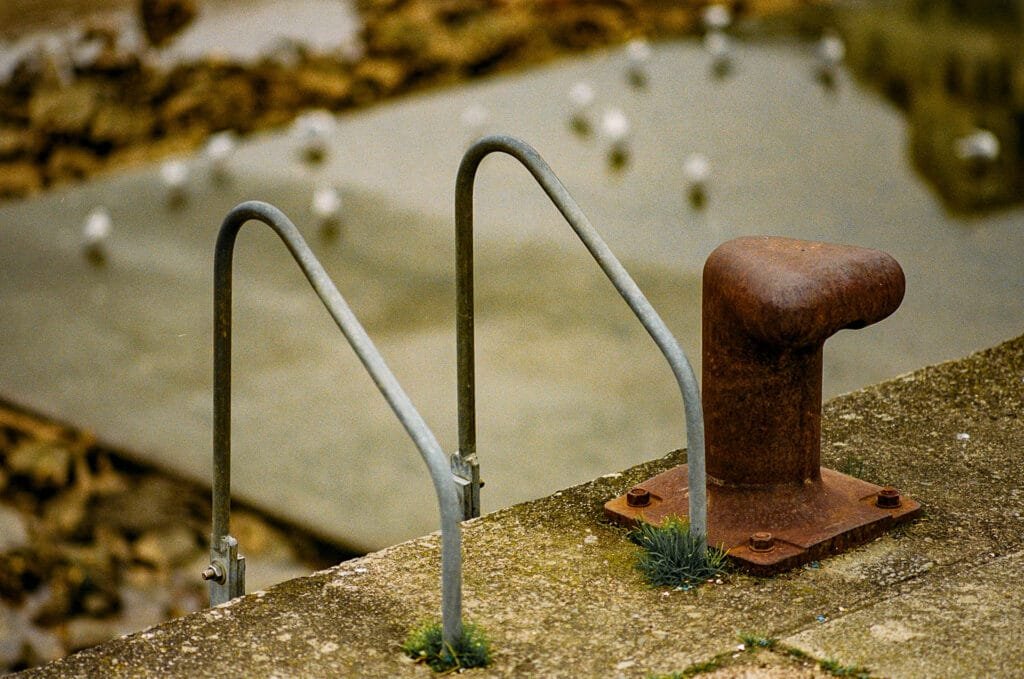 Bollard rouillé et échelle en métal sur le quai d’un port à marée basse à Pornic.