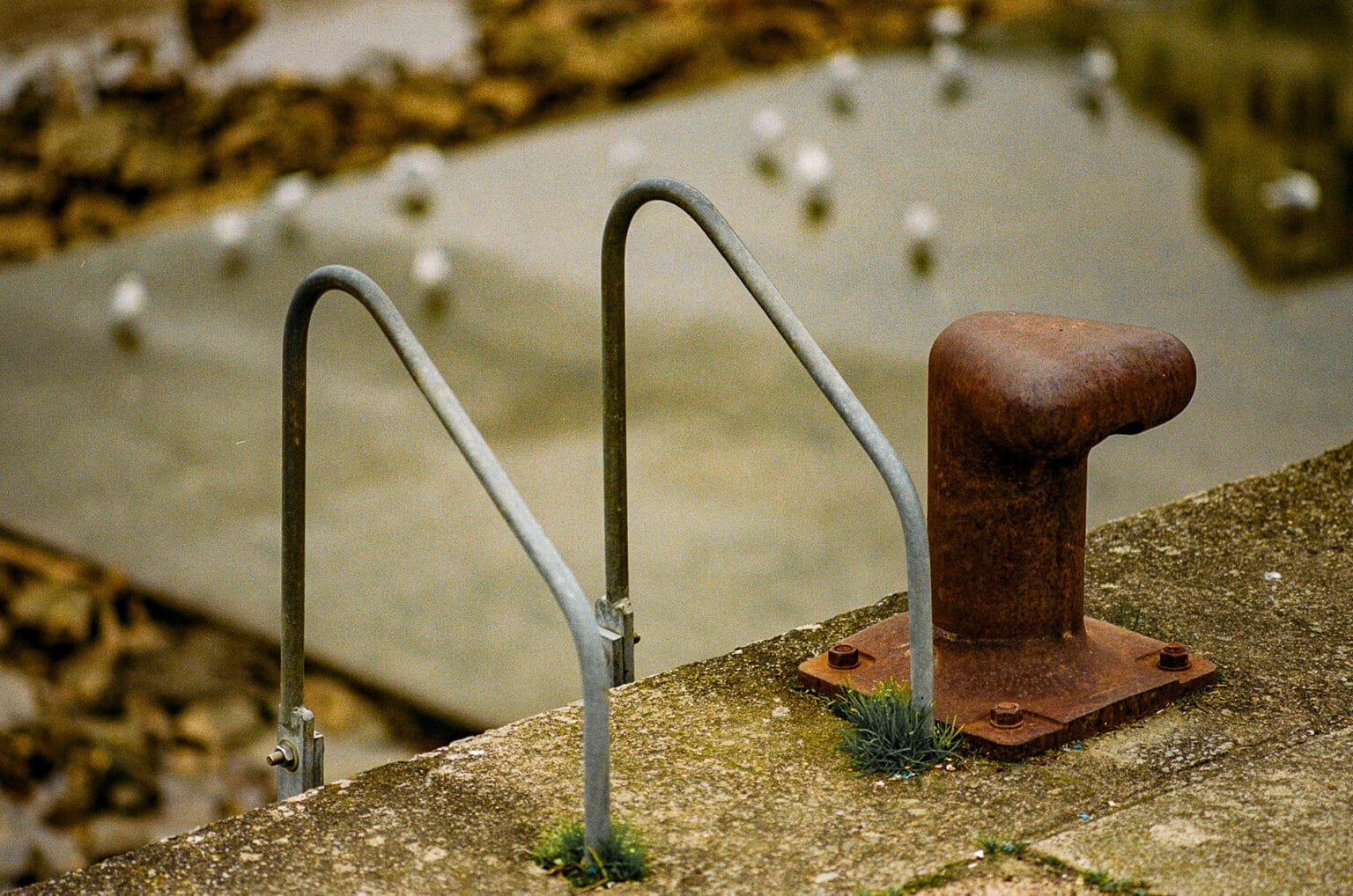 Bollard rouillé et échelle en métal sur le quai d’un port à marée basse à Pornic.