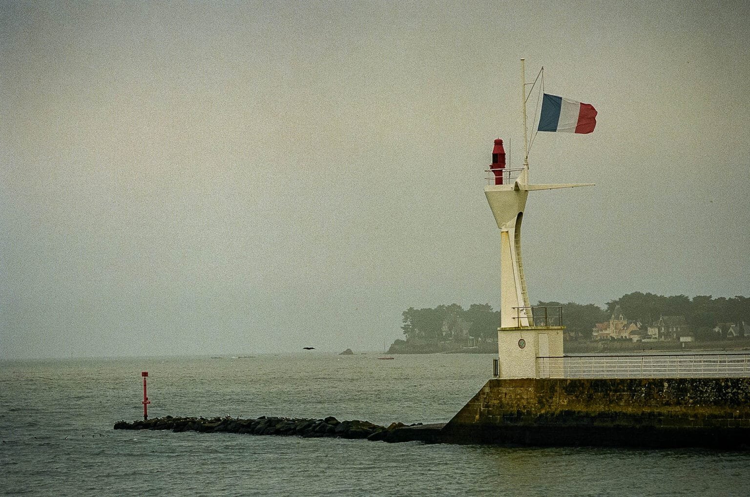 Feu de signalisation et drapeau français flottant au vent à l’entrée du port de Pornic.