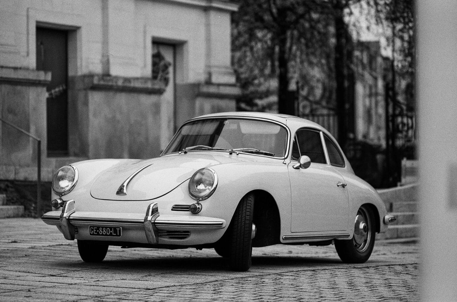 Vue d’ensemble d’une Porsche 356 garée devant l’hôtel Radisson à Nantes, en noir et blanc.
