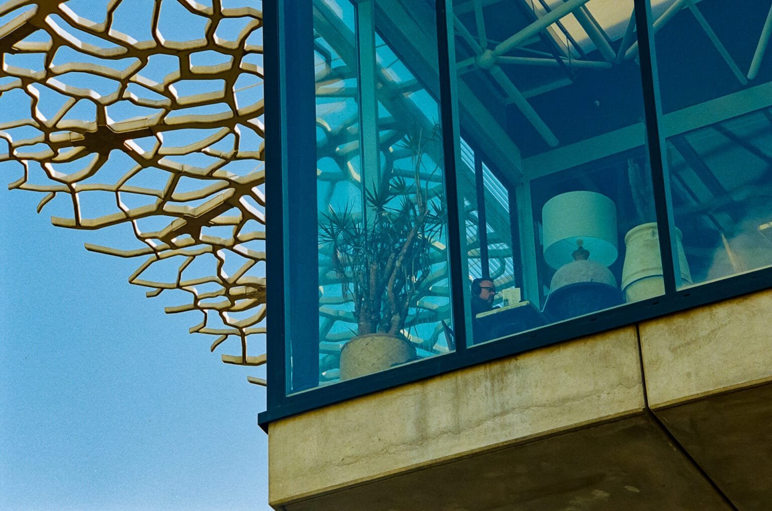 Vue du restaurant ZAW à la gare de Nantes, à travers la baie vitrée, avec une structure en béton et des motifs en résille métallique.