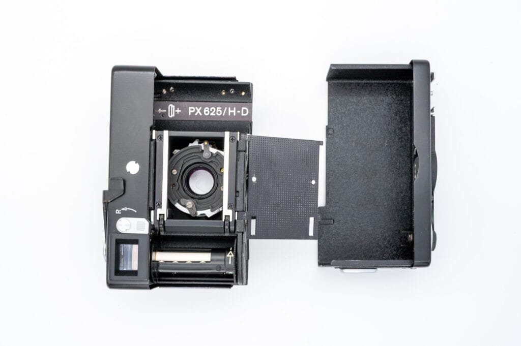 Vue de l’intérieur du Rollei 35 S avec le dos ouvert, montrant le compartiment à film, l’obturateur, et l’emplacement de la pile PX 625.