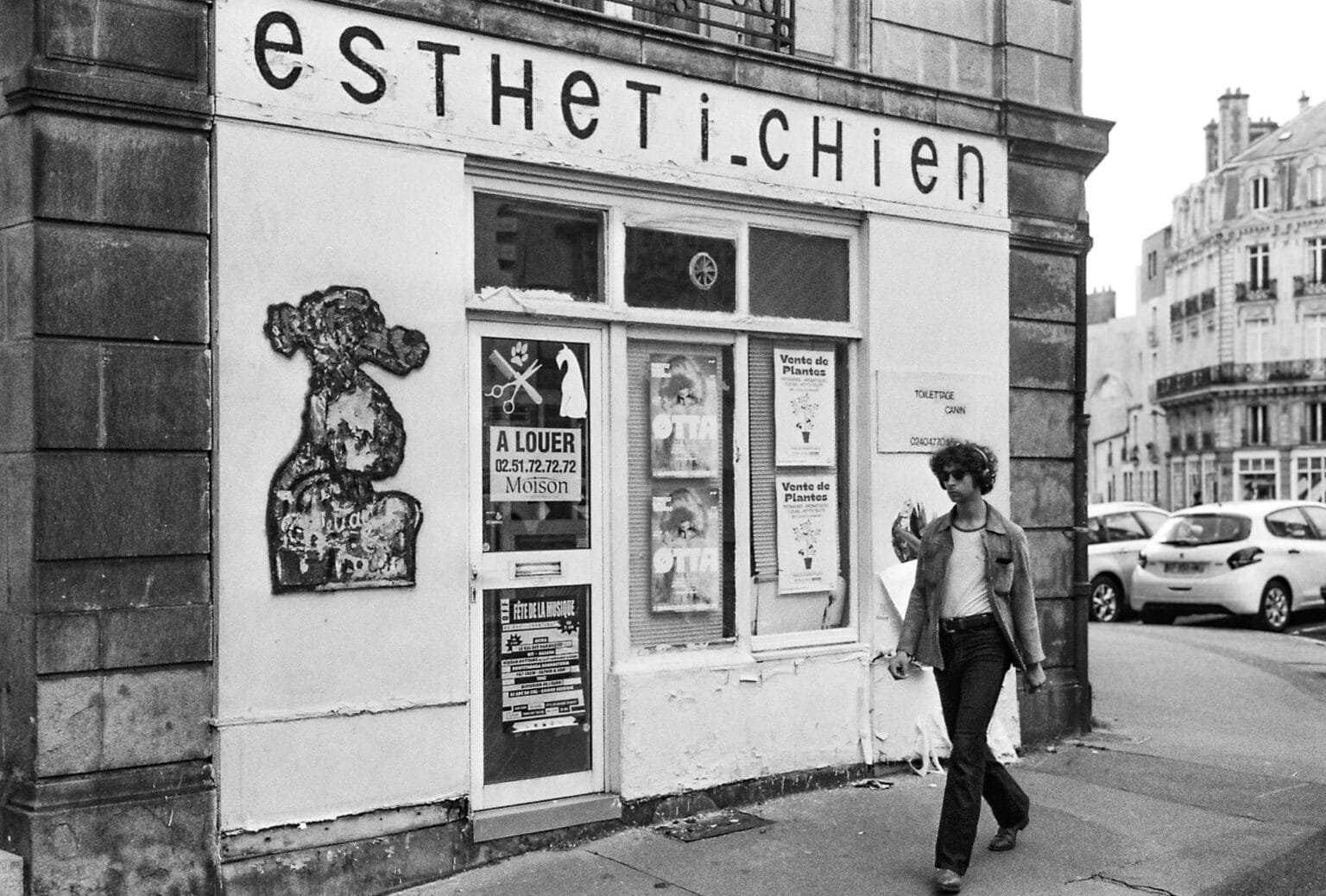 Ancien magasin de toilettage canin "estheti-chien" abandonné avec devanture défraîchie près de la cathédrale Saint-Pierre à Nantes. Passant en arrière-plan.