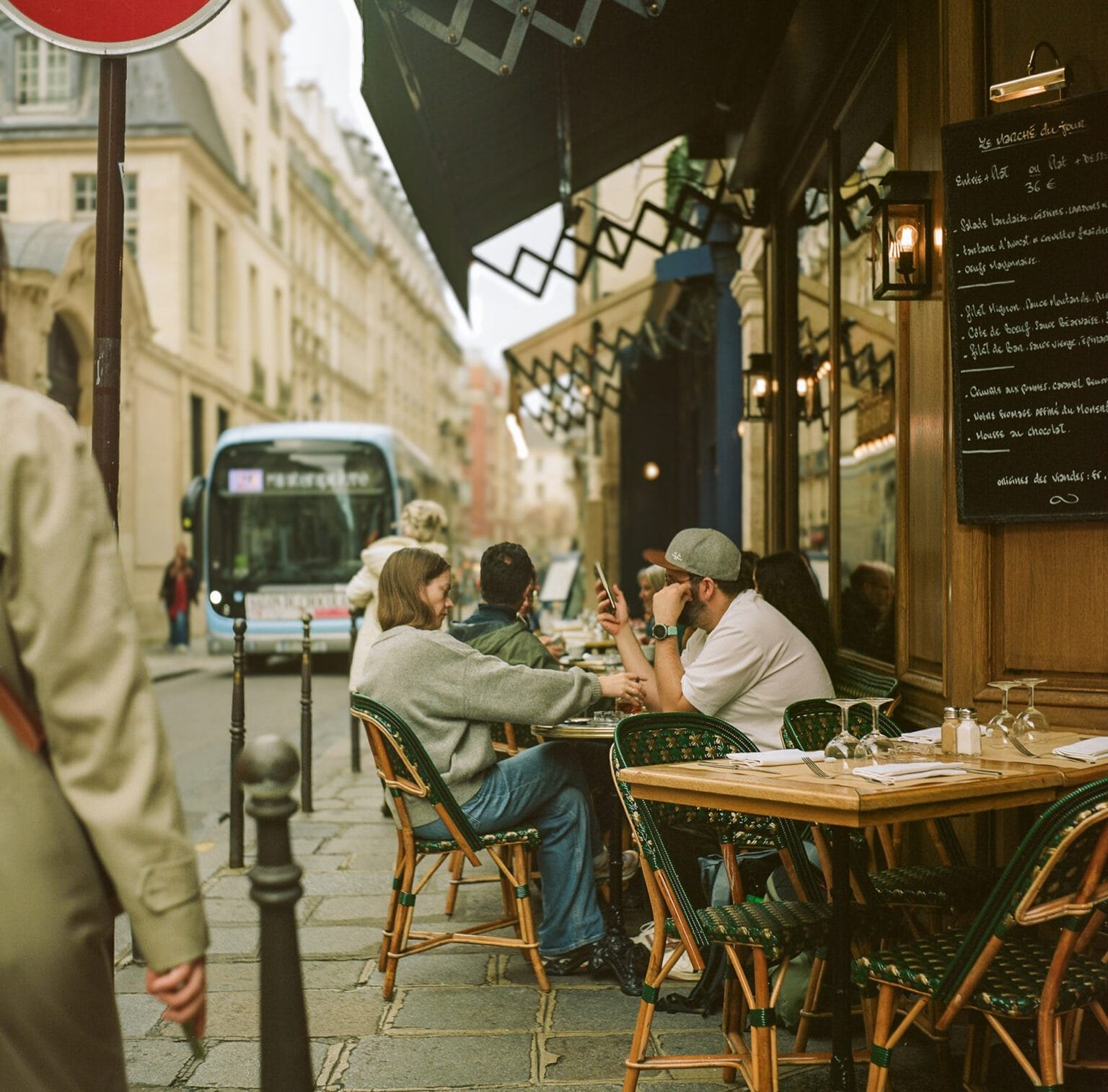 Groupe de personnes assises en terrasse d’un café dans le quartier du Marais à Paris, photographié avec un Yashica Mat 124G sur pellicule Kodak Portra 160.