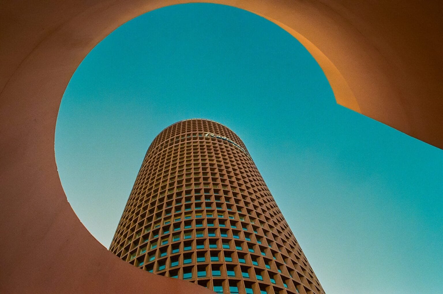 Vue de la Tour Part-Dieu, surnommée “Le Crayon”, cadrée à travers une ouverture circulaire de l’Auditorium de Lyon. Photo en Portra 160.