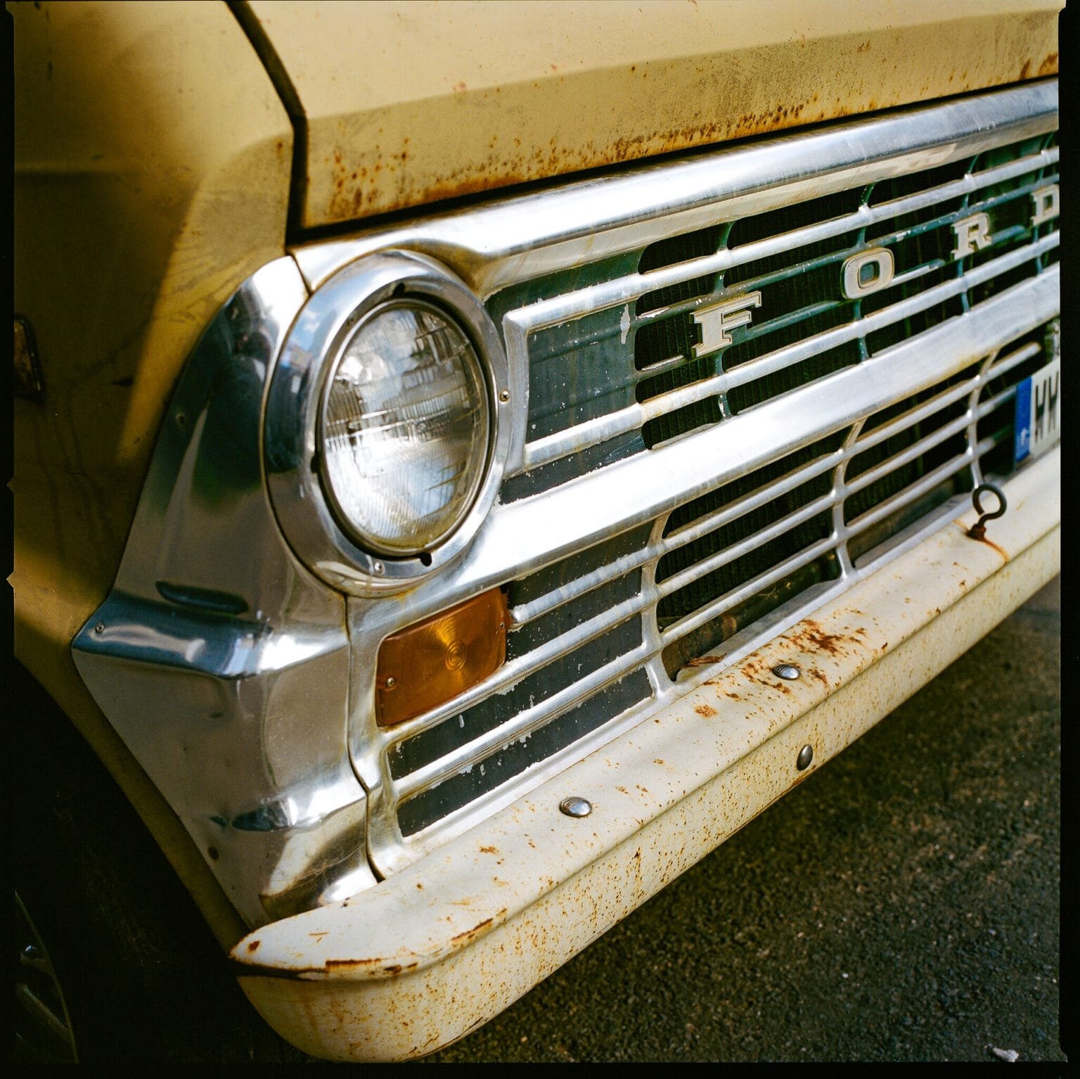 Gros plan sur la calandre chromée et rouillée d’un vieux Ford, garé dans les rues de Nantes.