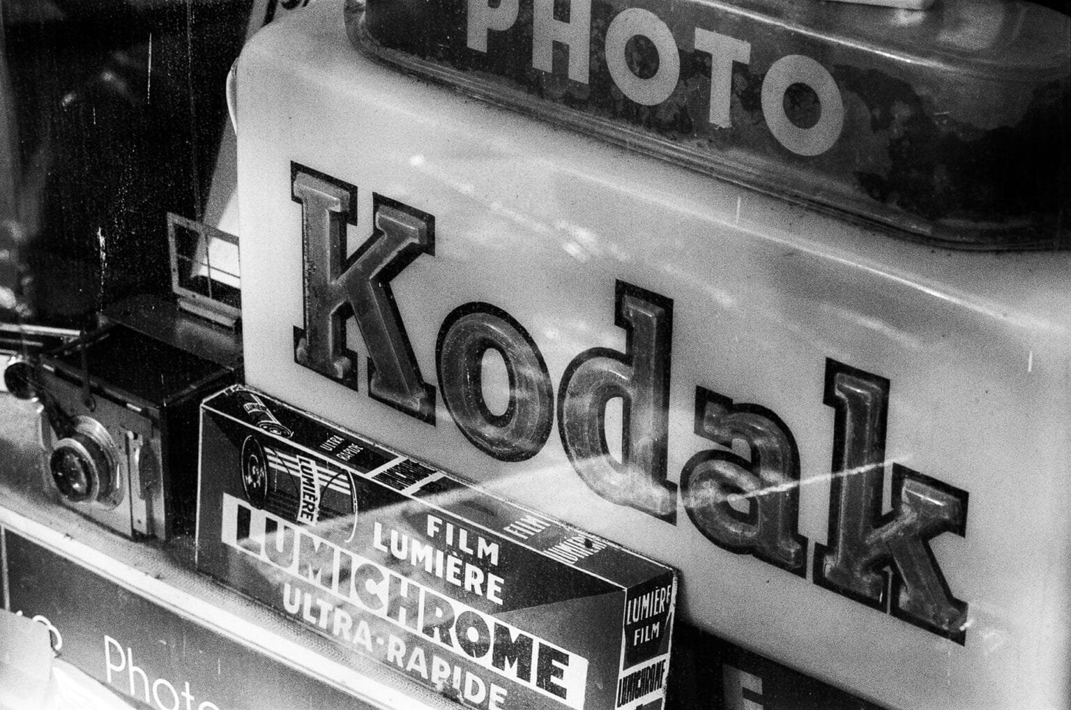 Vitrine d’un photographe à Saint-Nazaire avec un ancien logo Kodak et des boîtes de film Lumière.