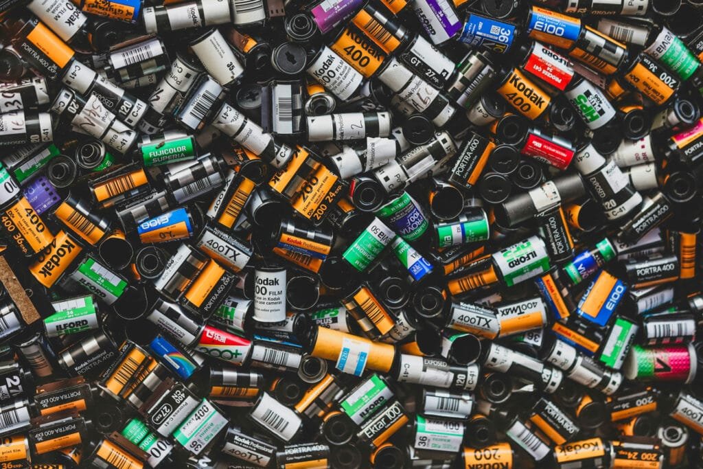 Collection variée de pellicules 35mm usagées, incluant des marques comme Kodak, Ilford, Fuji, et d’autres.