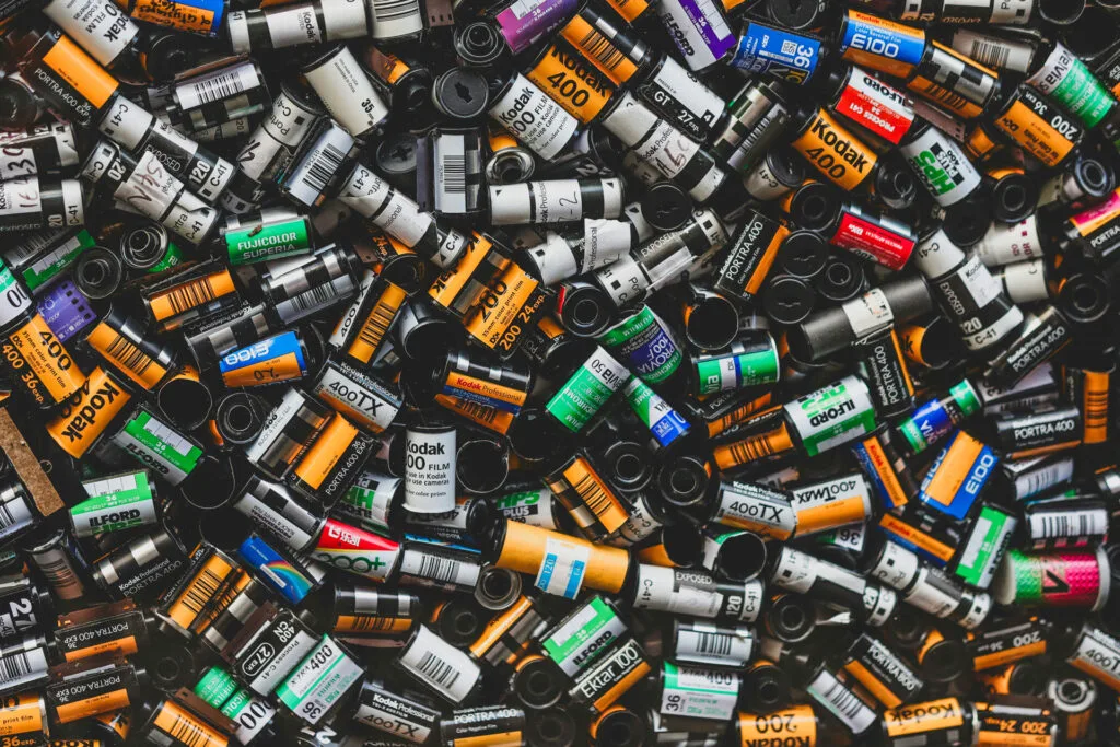 Collection variée de pellicules 35mm usagées, incluant des marques comme Kodak, Ilford, Fuji, et d’autres.