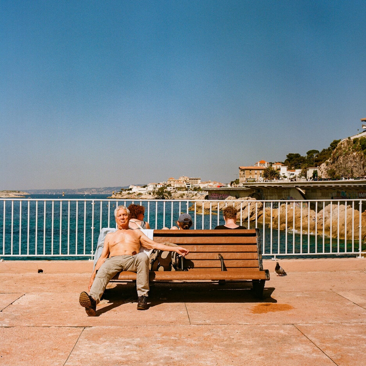 Homme torse nu assis sur un banc face à la mer Méditerranée, le long de la corniche Kennedy à Marseille, capturé en Kodak Gold avec un Hasselblad.