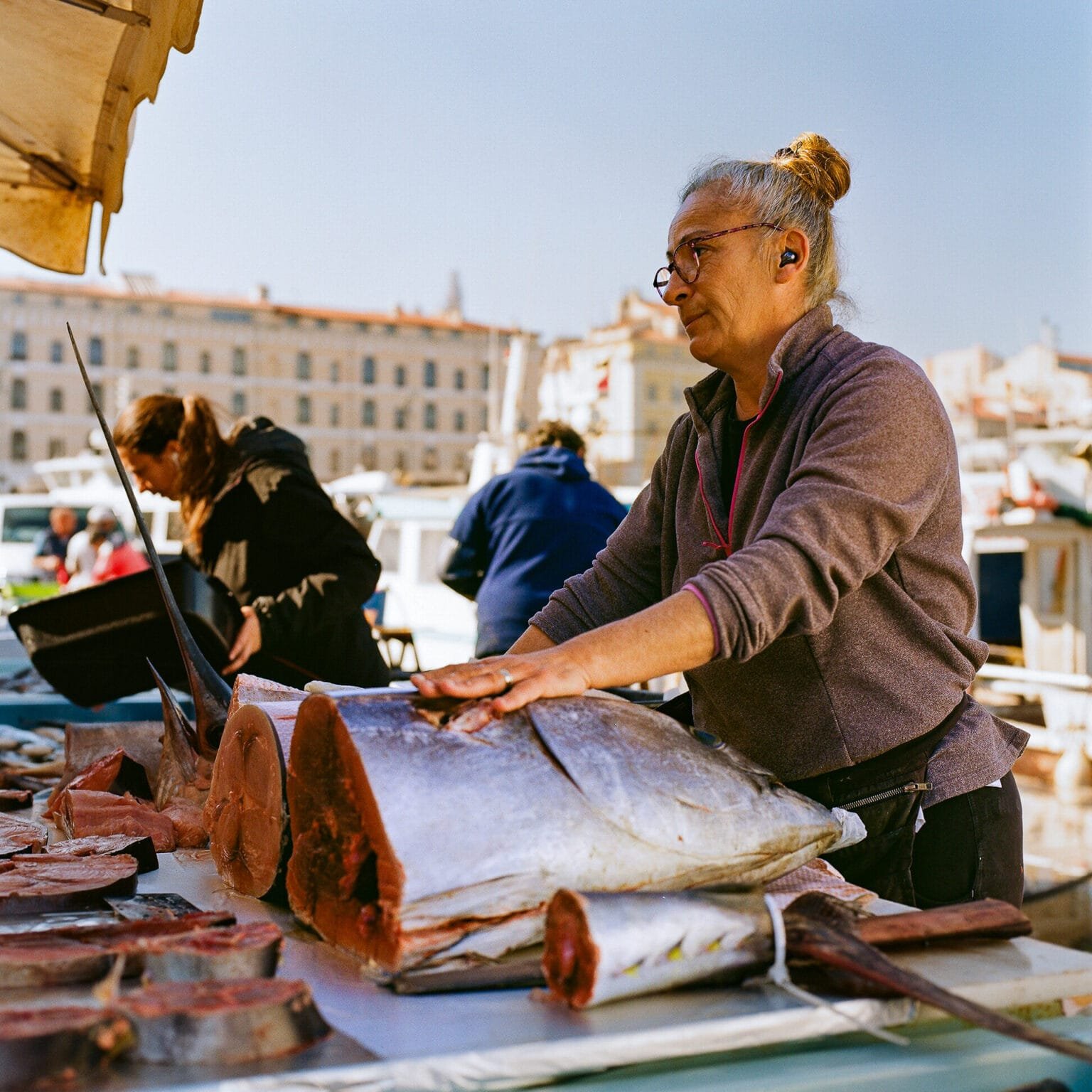 Poissonnière découpant un thon sur le marché du Vieux-Port de Marseille, photographiée avec un Hasselblad 500 C/M et une pellicule Kodak Gold 200.