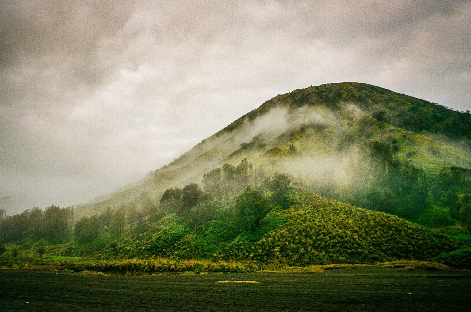 Colline verdoyante du mont Batok enveloppée de brume dans la caldeira de Tengger.