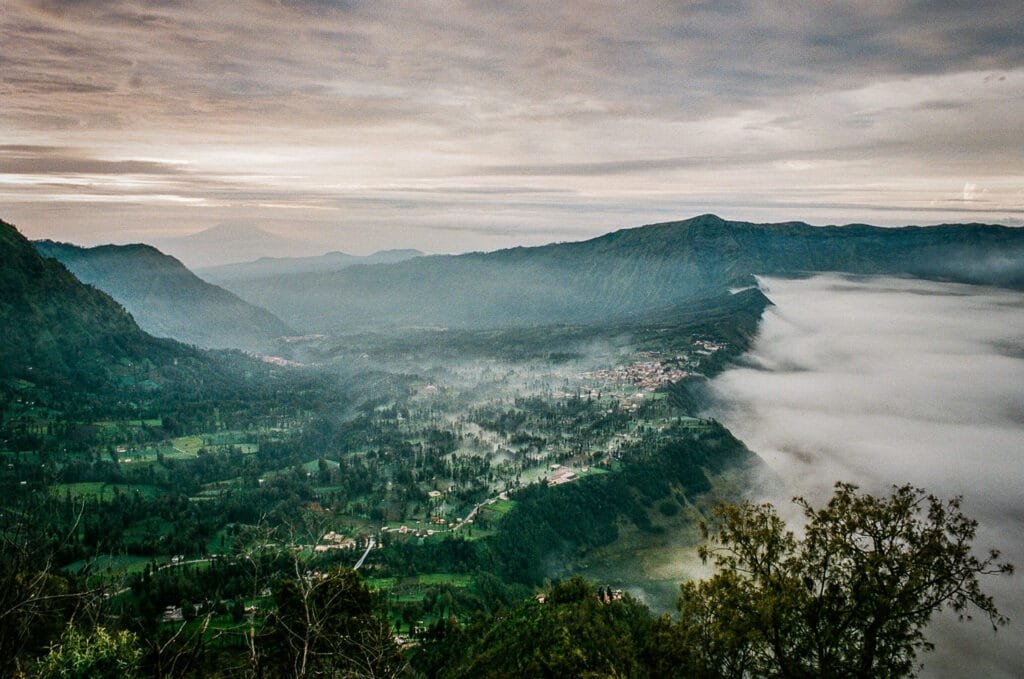 Vue aérienne sur la caldeira du Bromo au petit matin, avec les villages et la brume qui s’étendent dans la vallée.