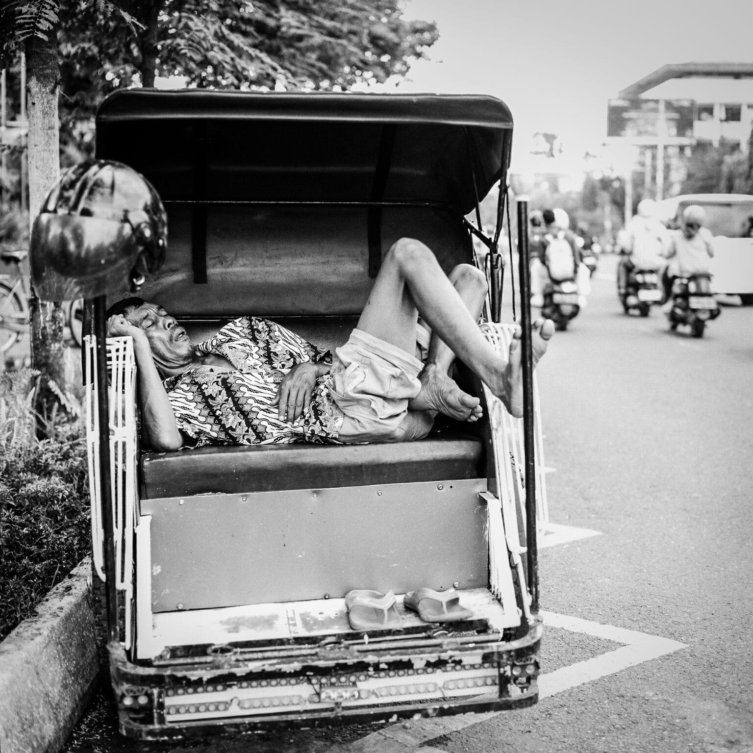 Homme endormi dans un becak traditionnel à Yogyakarta, photographié en noir et blanc avec un Hasselblad 500 C/M.