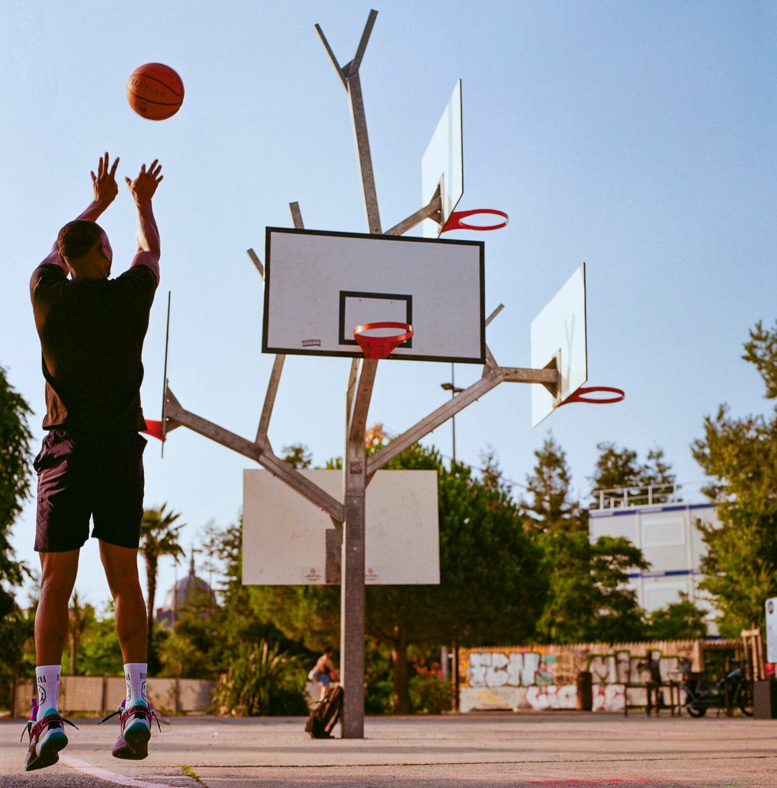 Joueur de basket en train de shooter devant une sculpture de paniers en forme d’arbre à Nantes