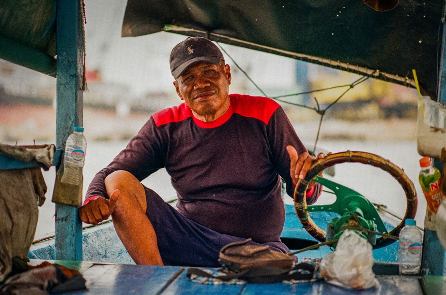 Portrait d’un batelier souriant à bord d’un petit bateau traditionnel dans le port de Jakarta, pris au Nikon F3 HP et Nikkor 50mm f/1.4.