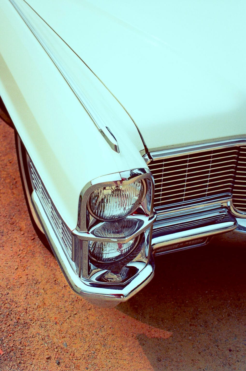 Gros plan sur l’avant d’une Cadillac vintage crème, photographiée sur un sol rouge à Tharon Plage