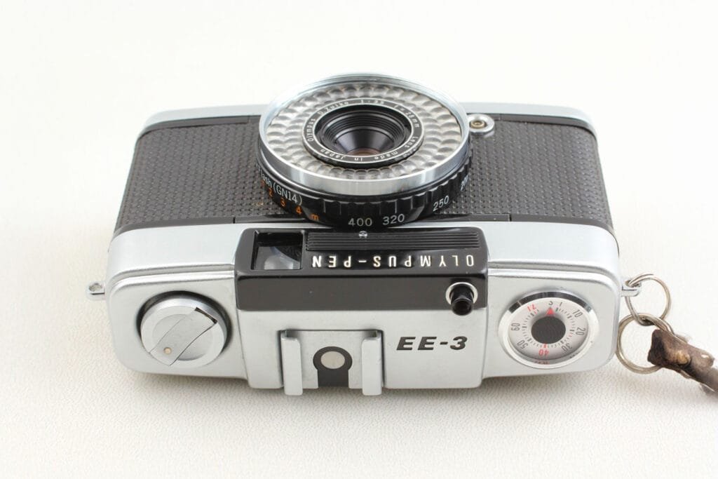 Vue de dessus de l’Olympus Pen EE-3 avec molette de rembobinage, sabot porte-accessoire et bague de sensibilité ASA.