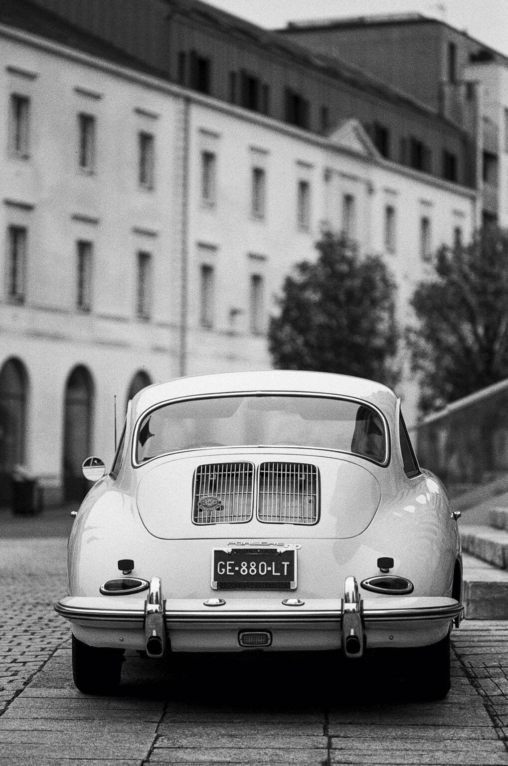 Vue arrière d’une Porsche 356 stationnée devant l’hôtel Radisson à Nantes, en noir et blanc