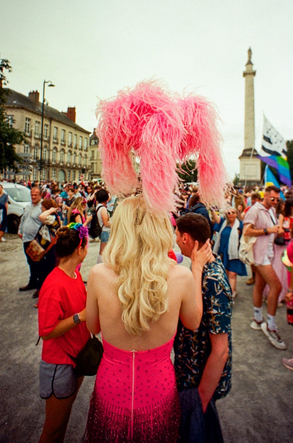 Personne en robe rose à plumes devant la statue Louis XVI lors de la Pride de Nantes.