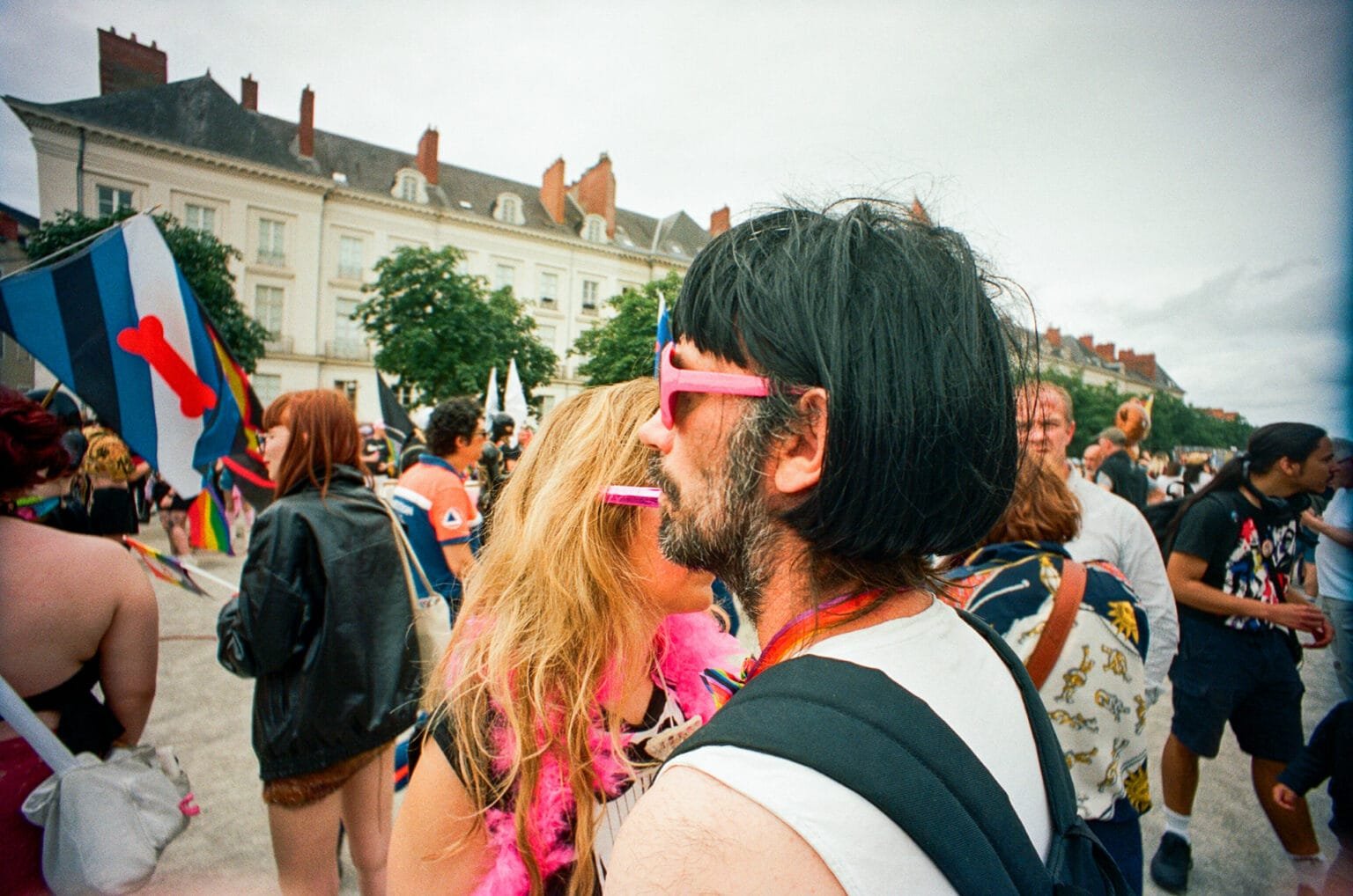 Couple portant des lunettes roses et des accessoires colorés à la Pride de Nantes.
