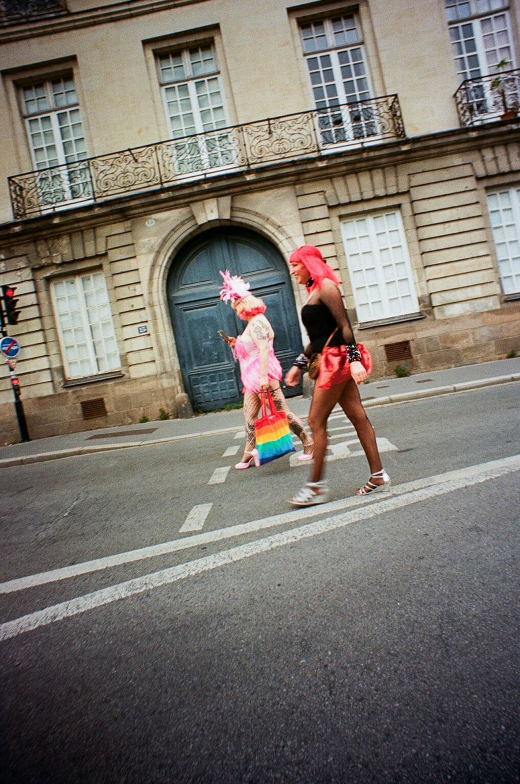 Deux personnes déguisées en rose traversent la rue lors de la Pride de Nantes.